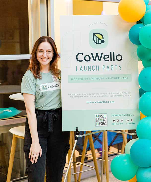 Mackenzie in front of CoWello launch party sign